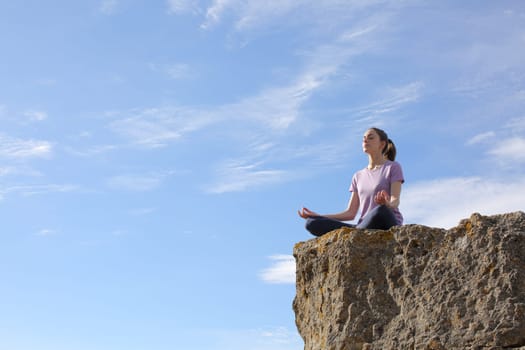 Yogi practicing yoga in the top of a cliff