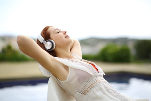 Relaxed woman listening to music resting in a pool
