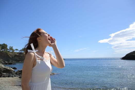 Happy woman in white screaming on the beach