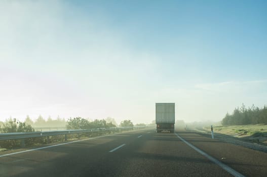 Driving behind a truck under morning haze. Bad-weather driving concept