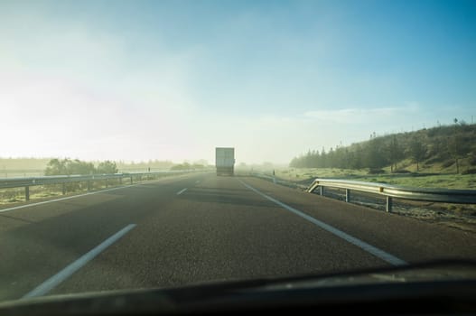 Driving behind a truck under morning haze. Bad-weather driving concept