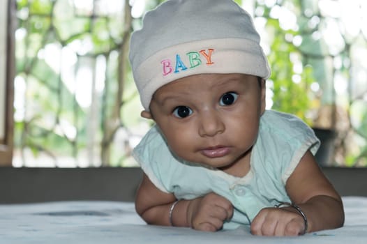 Cute baby lifting head. Closeup portrait. Happy baby boy looking and smiling at camera. Health care medical background. Sweet little infant toddler. Indian ethnicity. Developmental milestone for baby.