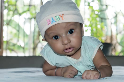 Cute baby lifting head. Closeup portrait. Happy baby boy looking and smiling at camera. Health care medical background. Sweet little infant toddler. Indian ethnicity. Developmental milestone for baby.