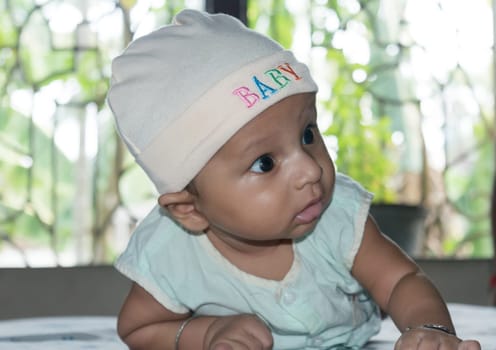 Cute baby hold his head up. Closeup portrait. Happy baby boy smiling looking away. Health care medical background. Sweet little infant toddler. Indian ethnicity. Developmental milestone for baby.