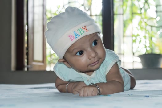 Cute baby hold his head up. Closeup portrait. Happy baby boy smiling looking away. Health care medical background. Sweet little infant toddler. Indian ethnicity. Developmental milestone for baby.