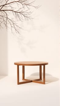 A simple wooden table with a round top filled with a coating that provides sunlight. The delicate shadows of leafy branches play on the textured cream wall in the background. High quality photo