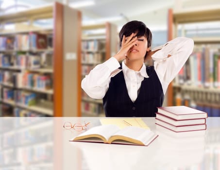 Young Female Mixed Race Student Stressed and Frustrated In Library with Blank Pad of Paper and Books.