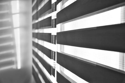 Sun shining through window roller blinds throwing shadows on the wall. Atmospheric mood. Selective focus.