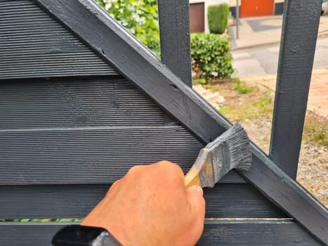 Brushing garden fence with brush - close-up