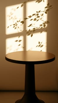 A simple wooden table with a round top filled with a coating that provides sunlight. The delicate shadows of leafy branches play on the textured cream wall in the background. High quality photo