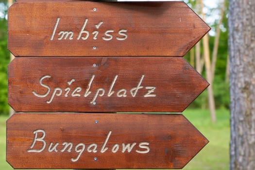 Signpost on a campsite in Germany with the inscription snack bar, playground, bungalows (Imbiss, Spielplatz, Bungalows)