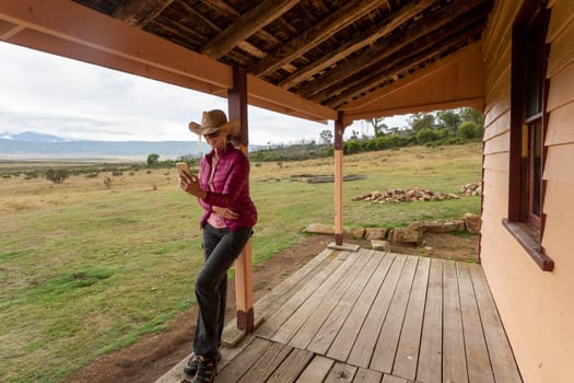 Country woman using her mobile phone in a rural farmland setting