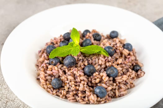 Fresh and healthy vegan rice bowl served with bilberry fruits. Diet concept. Copy space for recipes. Image for your food blog on socials