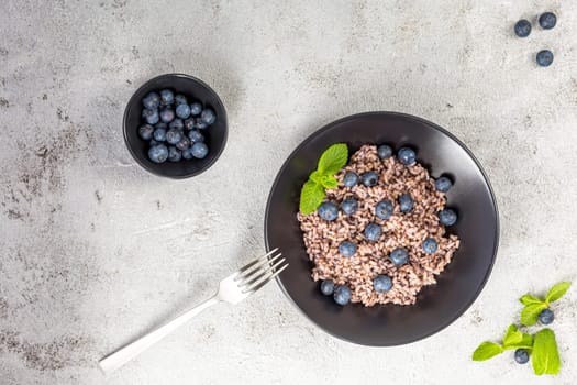 Fresh and healthy vegan rice bowl served with bilberry fruits. Diet concept. Copy space for recipes. Image for your food blog on socials