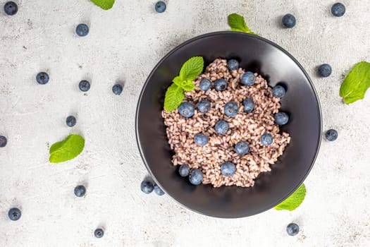 Fresh and healthy vegan rice bowl served with bilberry fruits. Diet concept. Copy space for recipes. Image for your food blog on socials