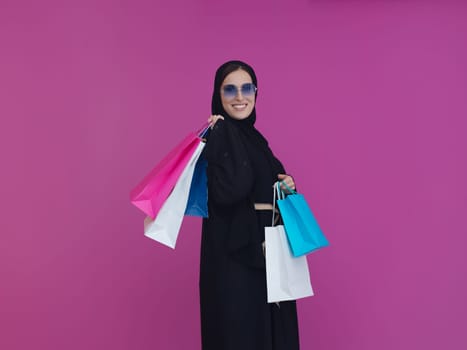Happy muslim girl posing with shopping bags. Arabic woman wearing traditional black clothes and sunglasses representing rich and luxurious lifestyle