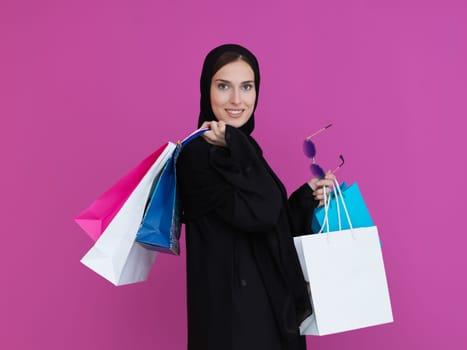 Happy muslim girl posing with shopping bags. Arabic woman wearing traditional black clothes and sunglasses representing rich and luxurious lifestyle