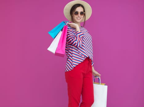 Young woman with shopping bags on pink background. Happy girl posing with new purchases after a day of big sale. Black Friday concept