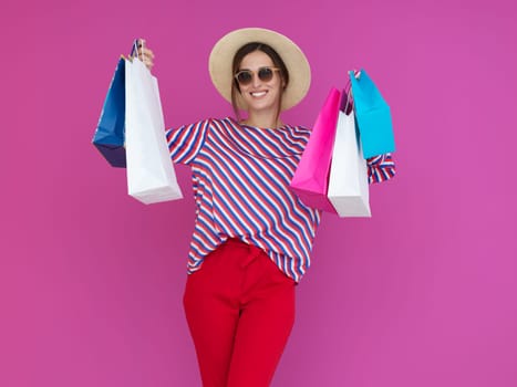 Young woman with shopping bags on pink background. Happy girl posing with new purchases after a day of big sale. Black Friday concept
