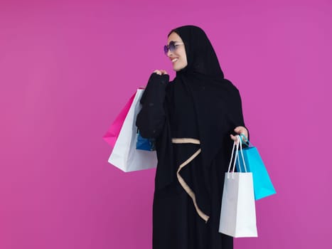 Happy muslim girl posing with shopping bags. Arabic woman wearing traditional black clothes and sunglasses representing rich and luxurious lifestyle