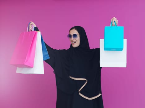 Happy muslim girl posing with shopping bags. Arabic woman wearing traditional black clothes and sunglasses representing rich and luxurious lifestyle