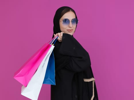 Happy muslim girl posing with shopping bags. Arabic woman wearing traditional black clothes and sunglasses representing rich and luxurious lifestyle