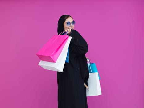 Happy muslim girl posing with shopping bags. Arabic woman wearing traditional black clothes and sunglasses representing rich and luxurious lifestyle