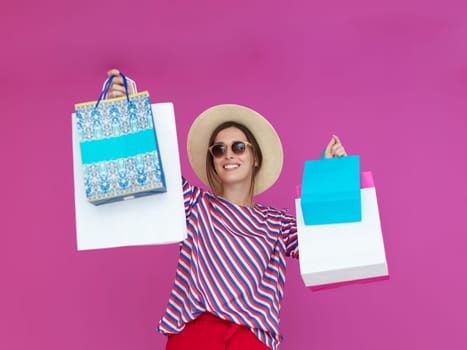 Young woman with shopping bags on pink background. Happy girl posing with new purchases after a day of big sale. Black Friday concept