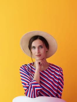 Portrait of young woman sitting on the chair isolated on yellow background. Female model in casual and modern clothes posing in the studio