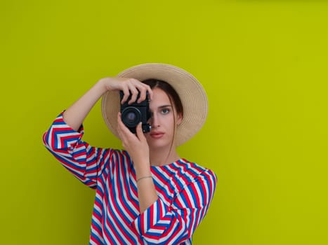 Portrait of beautiful female photographer shooting close up. Say cheese. Young smiling woman holding camera isolated on green background