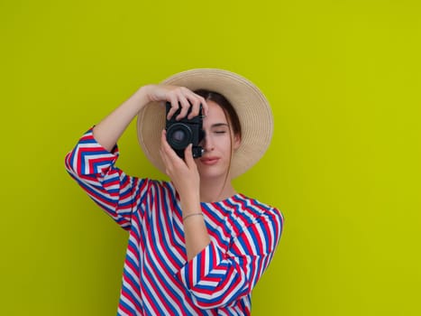 Portrait of beautiful female photographer shooting close up. Say cheese. Young smiling woman holding camera isolated on green background