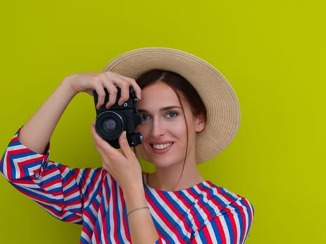 Portrait of beautiful female photographer shooting close up. Say cheese. Young smiling woman holding camera isolated on green background
