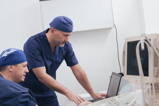 Orthopedist doctor team examining digital X-ray picture in clinic on a laptop computer. High quality photo. Selective focus