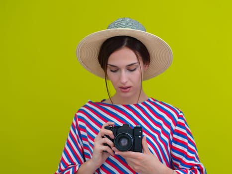 Portrait of beautiful female photographer close up. Say cheese. Young smiling woman holding camera and thinking how to make photo isolated on green background.