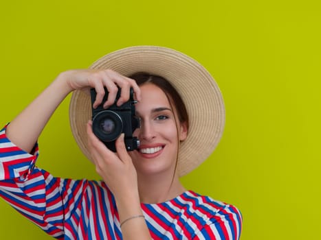 Portrait of beautiful female photographer shooting close up. Say cheese. Young smiling woman holding camera isolated on green background