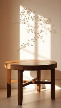 A simple wooden table with a round top filled with a coating that provides sunlight. The delicate shadows of leafy branches play on the textured cream wall in the background. High quality photo