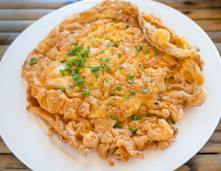 Crispy omelette with sliced green onion leaves on white plate. Thai style crab fried eggs food
