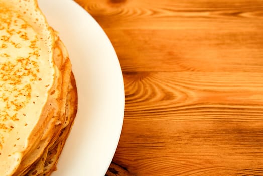 Pancakes on a plate on a wooden table. A large stack of fresh pancakes. Delicious healthy fresh pancakes. Place for advertising, logo, lettering, layout, mockup.