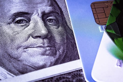 Benjamin Franklin's face on a hundred-dollar bill next to a credit card. Close-up. A hundred-dollar American bill with the eyes of Benjamin Franklin. Color style. Layout, template, layout.