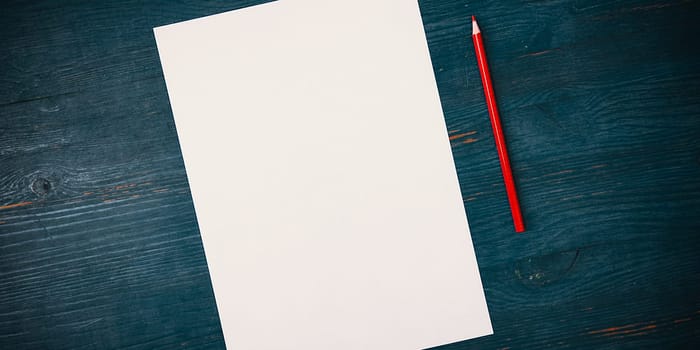 A blank white sheet and pencil for drawing on a wooden background with space for copying and lettering. Layout, mockup free space.