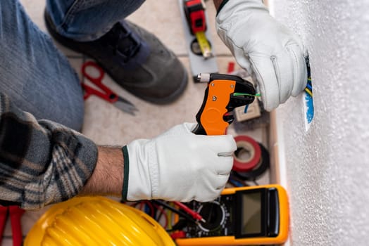 Top view. Electrician worker at work with wire stripper prepares the electrical cables of an electrical system. Working safely with protective gloves. Construction industry.