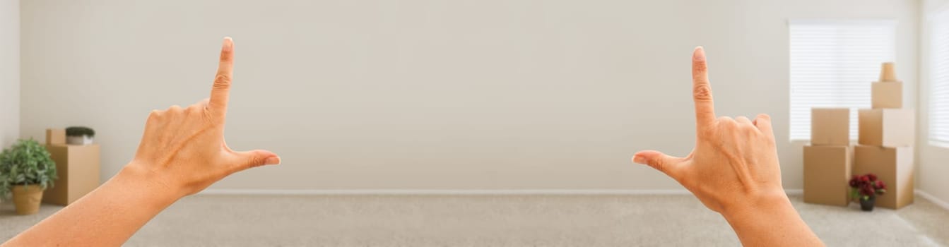 Female Hands Framing Blank Wall in Empty Room with Moving Boxes Banner.