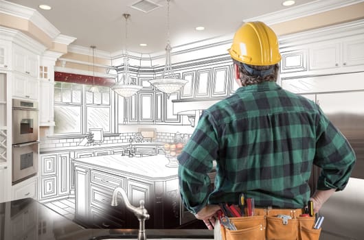 Male Contractor with Hard Hat and Tool Belt Looking At Custom Kitchen Drawing Photo Combination On White.