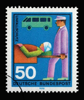 Stamp printed in Germany showing a rescuer carries injuries into a stretcher, volunteer emergency service accident protection, circa 1970
