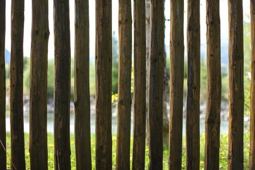Old wooden fence posts, with blurred river out of focus in background.