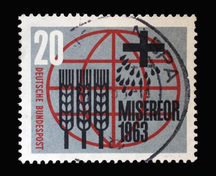 Stamp printed in Germany showing Stylized ears of corn, grains, cross and inscription in front of the globe honoring Miserior freedom from hunger, circa 1963