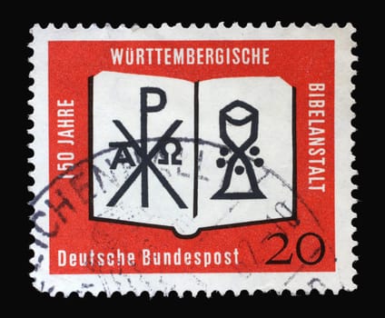 Stamp printed in Germany showing an open Bible with a monogram of Christ and a chalice. 150 years of the Württemberg Bible Institute, circa 1962