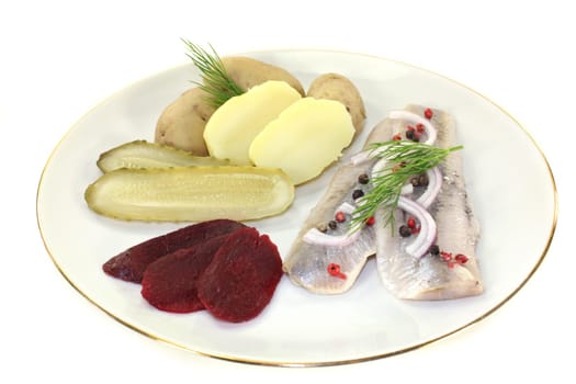a plate of matjes fillet,peel potatoes,beetroot and sour cucumbers