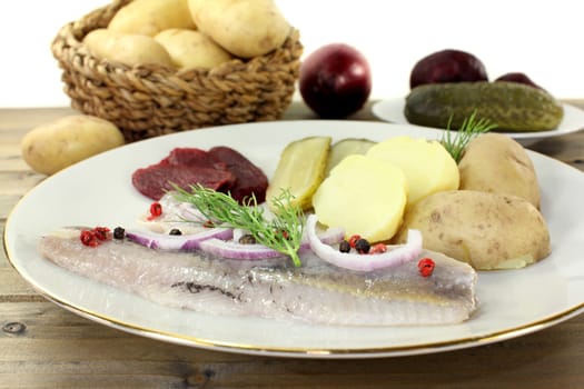 a plate of matjes fillet,peel potatoes,beetroot and sour cucumbers