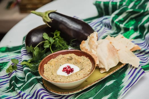 Traditional arabian eggplant dip baba ganoush with herbs and smoked paprika on a wooden background
